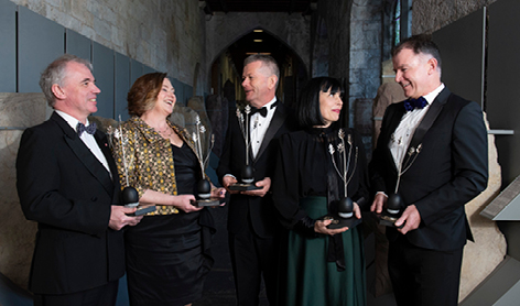 five awardees standing with their awards in the stone corridor ucc